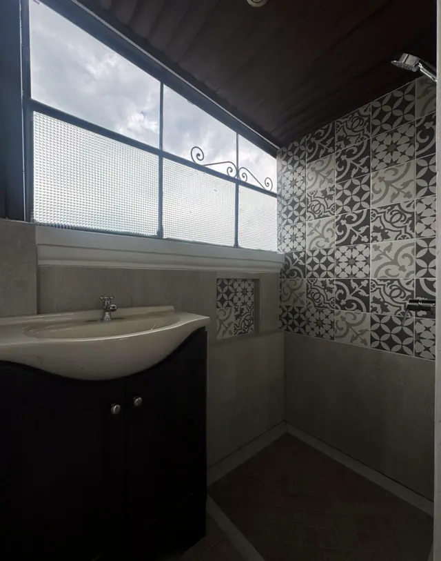 Salle de bain aux carreaux de ciment noirs et blancs avec une fenêtre sur le ciel