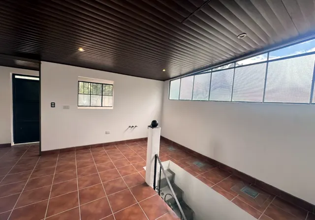 Pièce du troisième étage au plafond de bois avec une longue fenêtre